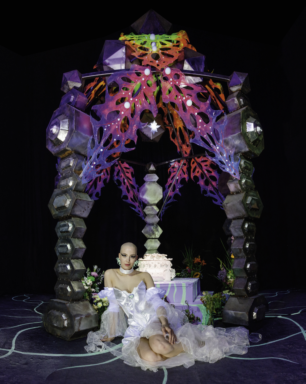 Photo of artist SOFF , also known as Sophie Ramirez, in front of the posthuman art installation Mausoleum at Kunstakademie Düsseldorf